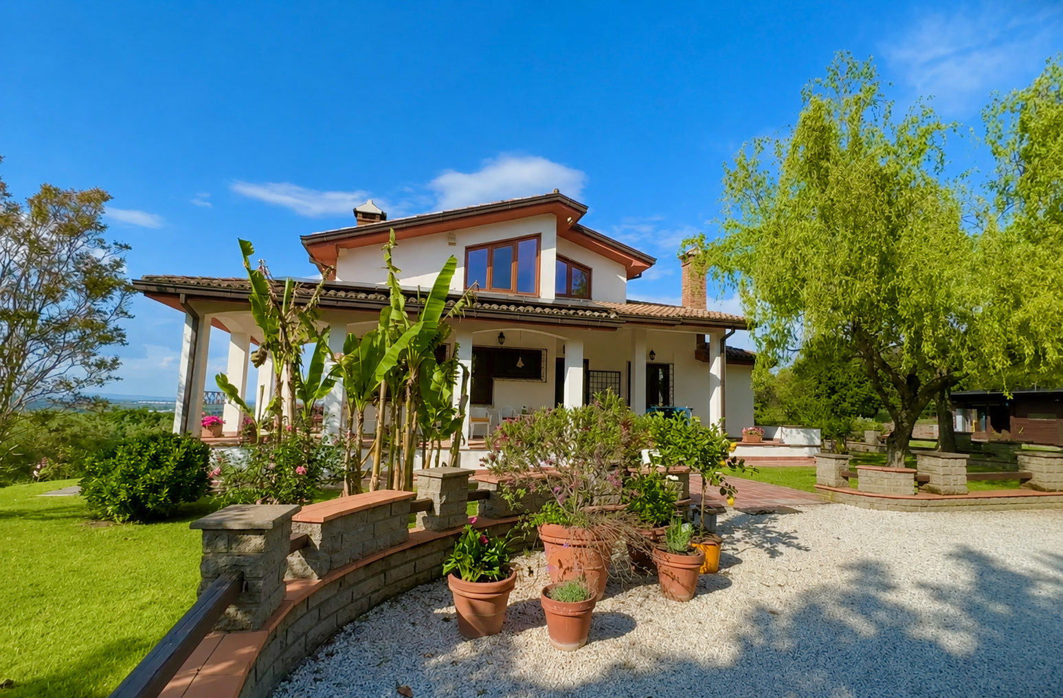 Vrijstaande Italiaanse villa met veranda, tuin en groen tijdens onze huizenzoektocht in Italië.